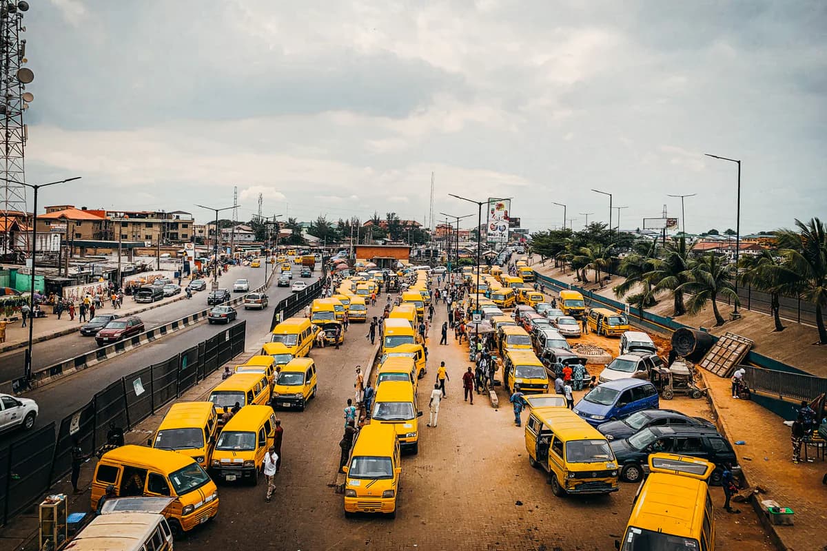 A busy Lagos transport corridor with yellow buses, pedestrians and roadside commerce